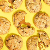 Biscoff New York Cookie with white and milk chocolate chips and gooey Biscoff spread filling on yellow background.